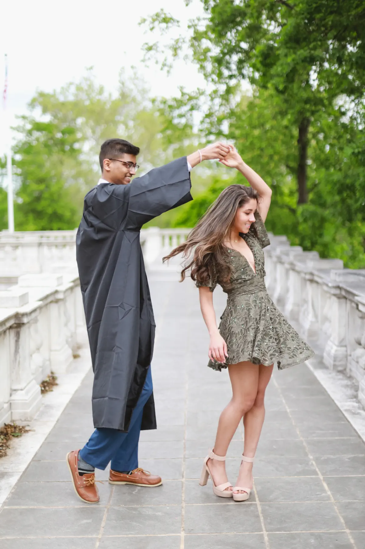 Naga twirling Lata on a stone walkway in his graduation gown