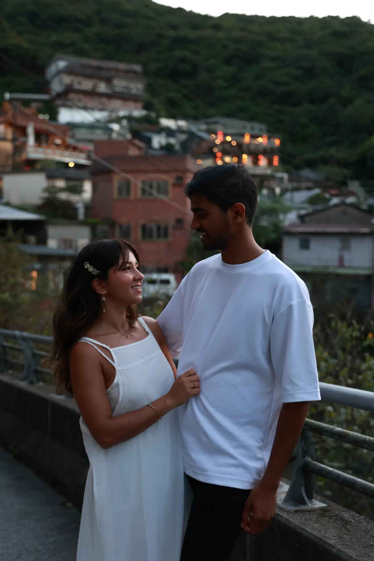 Naga and Lata dressed in white above a hillside town at dusk