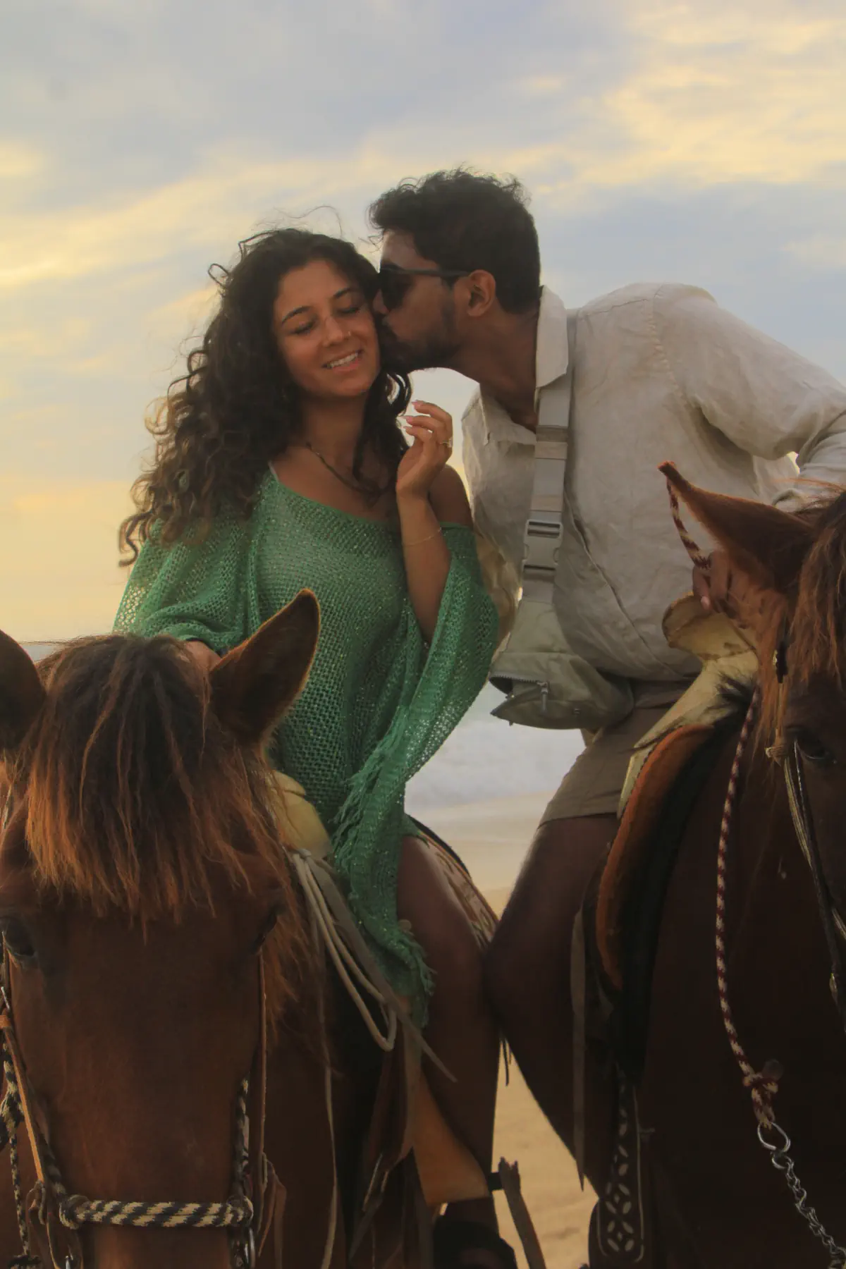 Naga kissing Lata's cheek while riding horses along the beach