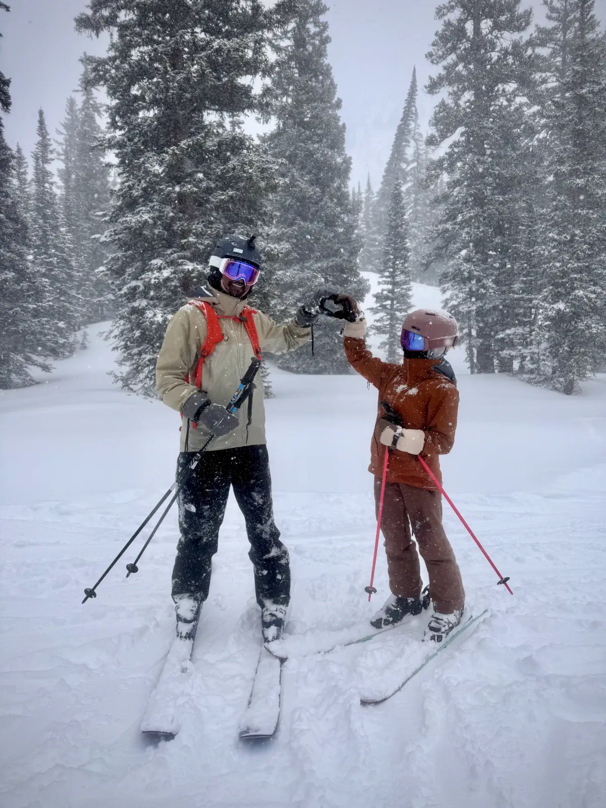 Naga and Lata bumping gloves on a snowy ski run